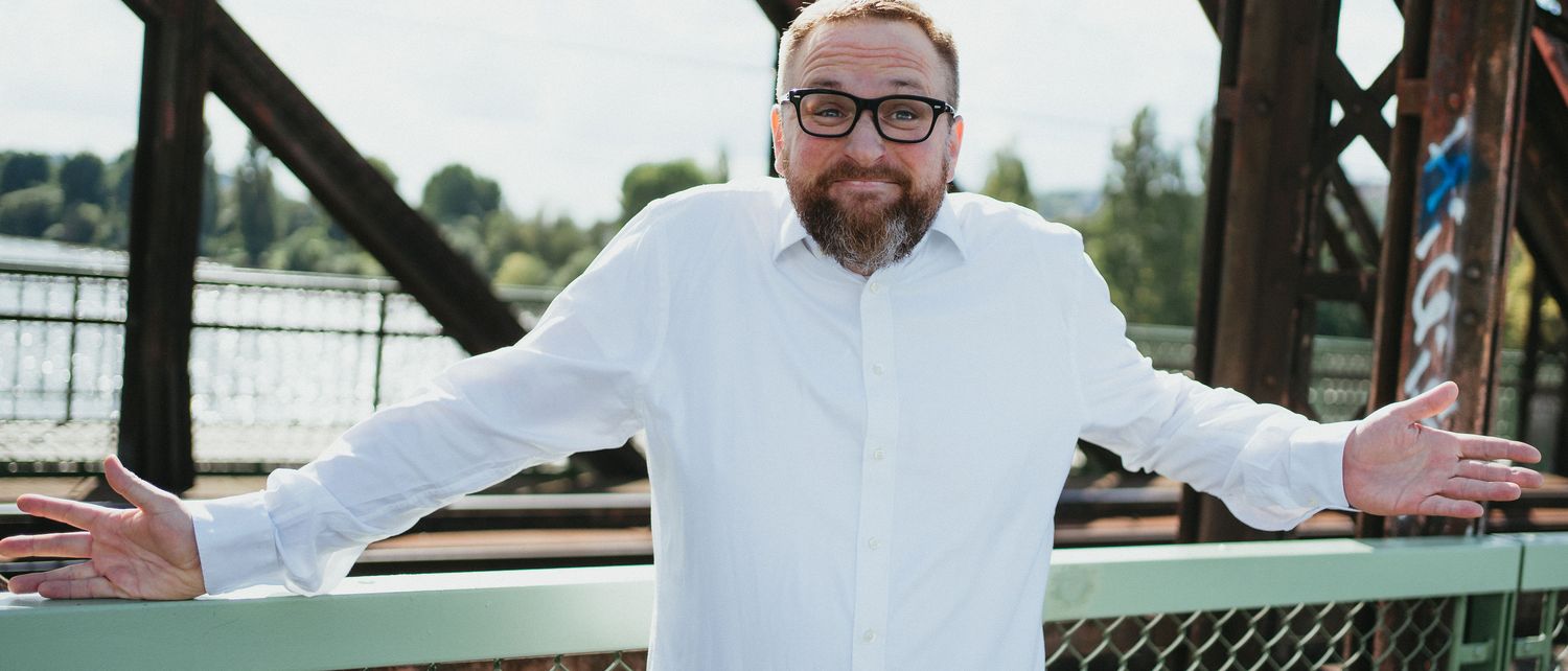 Ondřej Nečas s rozpaženýma rukama na železném mostě nad Vltavou